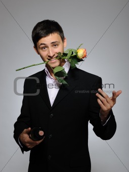 Handsome romantic young man holding rose flower and vine bottle 