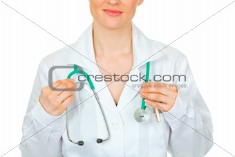 Medical doctor woman straightening stethoscope. Close-up.
