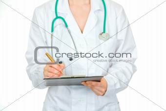 Medical female doctor making notes in document. Close-up.
