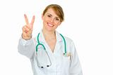 Smiling medical doctor woman showing victory gesture
