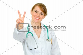 Smiling medical doctor woman showing victory gesture
