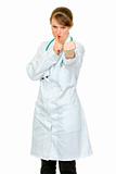Angry  medical doctor woman with finger at mouth and threaten with fist
