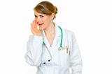  Smiling medical doctor woman holding her hand near mouth and secretly reporting good news
