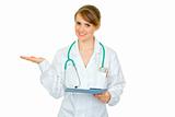Smiling doctor woman with medical chart presenting something on empty hand
