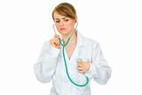 Concentrated doctor woman listening to her heart with stethoscope 

