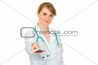 Smiling medical female doctor holding packs of pills in hand

