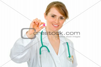 Smiling medical doctor woman holding  pill in hand
