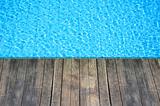 wood floor beside the blue swimming pool