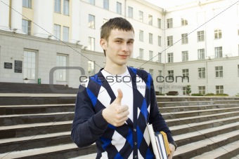 Male student on campus with textbooks. Thumbs up