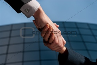 Handshake unrecognizable business man and woman on modern building background