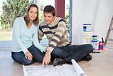 Couple sitting on the floor with blueprint of their new house