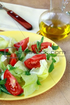 fresh salad with tomato and arugula, olive oil in the background