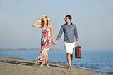couple on beach with travel bag