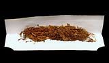 tobacco and rolling paper on black background