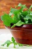 wooden cup with a green fresh arugula on the table