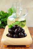 black olives and a bottle of oil on a wooden stand