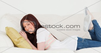 Attractive red-haired woman posing while lying on a sofa