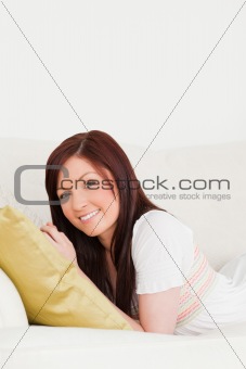 Beautiful red-haired woman posing while lying on a sofa