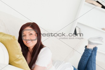 Good looking red-haired woman posing while lying on a sofa