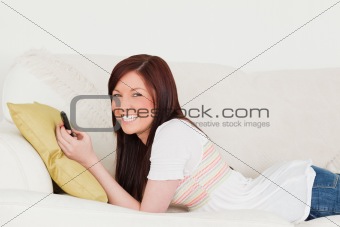 Attractive red-haired female writing a text on her phone while l