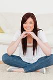 Beautiful red-haired woman posing while sitting on a carpet