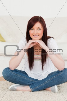 Beautiful red-haired woman posing while sitting on a carpet