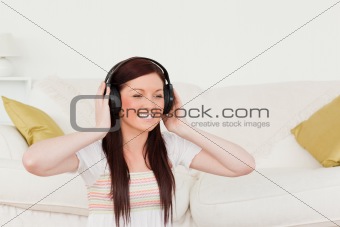 Gorgeous red-haired woman listening to music with headphones whi