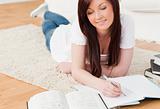 Beautiful red-haired girl studying for while lying on a carpet