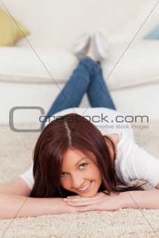 Gorgeous red-haired female posing while lying on a carpet