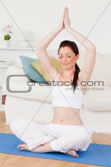 Charming female doing yoga on a gym carpet