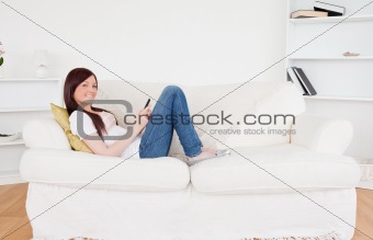 Good looking red-haired female writing a text on her phone while