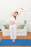 Cute red-haired woman stretching in the living room