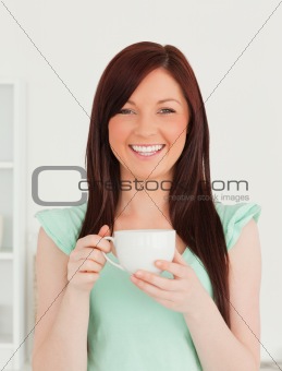 Pretty red-haired woman having her breakfast in the kitchen