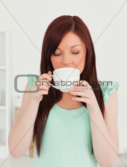 Beautiful red-haired woman having her breakfast in the kitchen