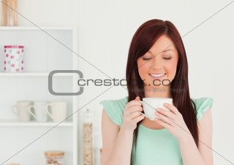 Cute red-haired woman having her breakfast in the kitchen