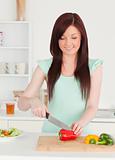Gorgeous red-haired woman cutting some vegetables in the kitchen