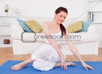 Attractive red-haired female stretching in the living room