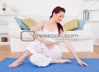Good looking red-haired female stretching in the living room