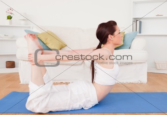 Young gorgeous red-haired female stretching in the living room