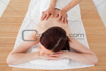 Closeup of a young beautiful red-haired woman receiving a massage in a spa centre