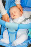 Mother's hand stroking head sleeping  in stroller baby
