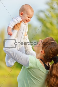 Happy mother playing with smiling baby girl in park
