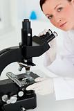 Cute red-haired scientist looking through a microscope
