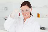 Cute red-haired scientist looking at a test tube in a lab