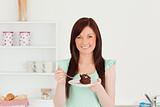 Good looking red-haired woman eating some cake in the kitchen