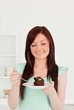 Attractive red-haired woman eating some cake in the kitchen