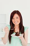 Pretty red-haired woman eating some cake in the kitchen