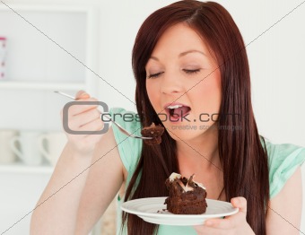 Gorgeous red-haired woman eating some cake in the kitchen
