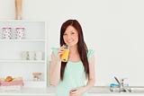 Beautiful red-haired woman enjoying a glass of orange juice in t