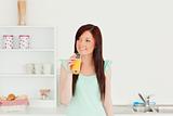 Good looking red-haired woman enjoying a glass of orange juice i
